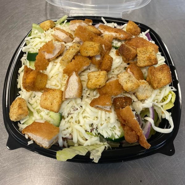 Alvino's Pizza chicken salad with shredded cheese, croutons, and fried chicken pieces in a plastic container.