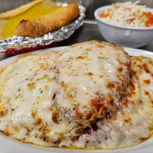 Cheesy baked pasta dish with a side of garlic bread and a salad from Alvino's Pizza.