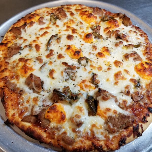 Alvino's Pizza with melted cheese, sausage, and peppers on a metal tray.