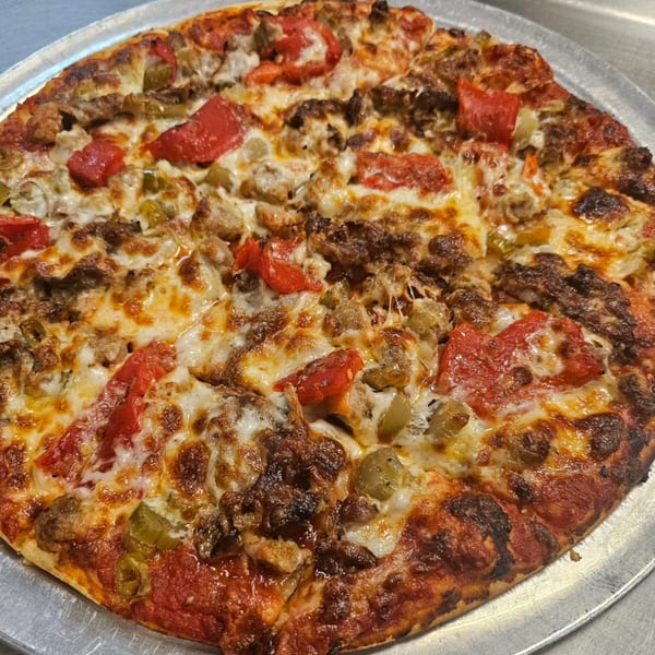 Alvino's Pizza with red peppers, green peppers, sausage, and ground beef on a metal tray.