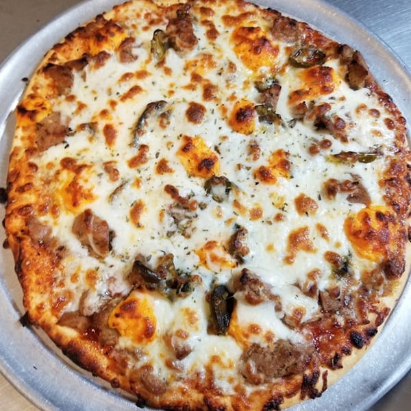 Alvino's Pizza with melted cheese, sausage, and mushrooms on a metal tray.